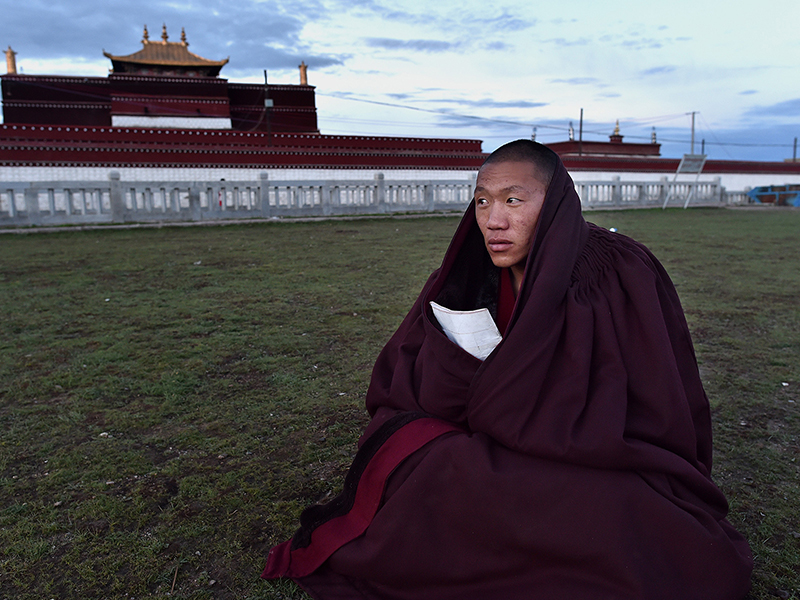 6月25日早晨，那曲县孝登寺草地上，一名僧人在诵佛经。